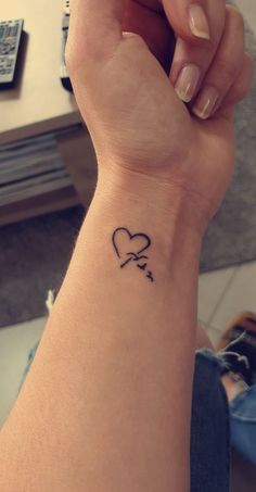 a woman's wrist with a heart and arrow tattoo on the left side of her arm