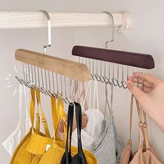 a person is holding two purses and hanging them on a coat rack with hooks