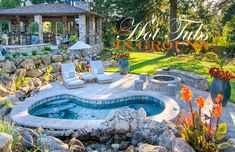 an outdoor hot tub surrounded by rocks and flowers