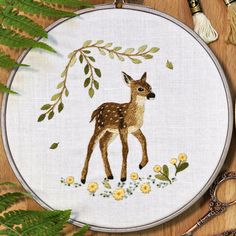 a cross stitch deer with flowers and leaves on it's face, next to some scissors