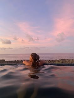 a woman is sitting in the water at sunset