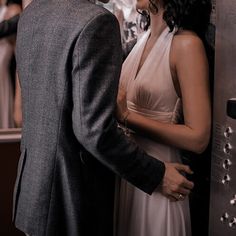 a man and woman standing next to each other in front of a metal wall with writing on it