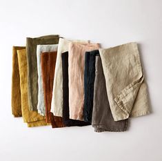 five pairs of linen pants lined up on a white background, each with different colors