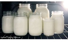 milk in glass jars are sitting on the rack inside an oven, and it's time to cook