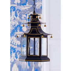 a black and gold lantern hanging from a ceiling with blue wallpaper in the background