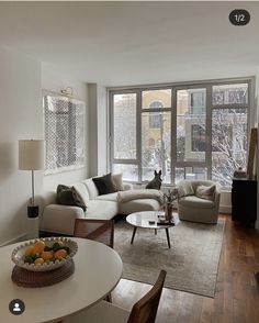 a living room filled with furniture and a white table in front of a large window