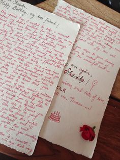 two pieces of paper with writing on them and a red rose sitting next to it