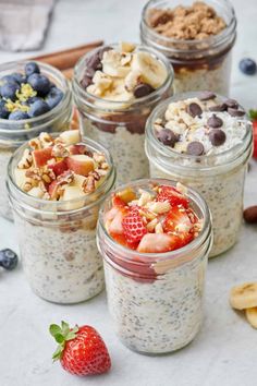 four mason jars filled with oatmeal, fruit and granola toppings