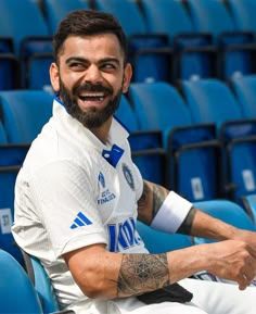 a man sitting in the stands at a sporting event with tattoos on his arm and chest