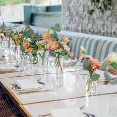 there are many vases with flowers in them on the long table at this restaurant