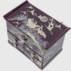 an elaborately painted wooden jewelry box with birds and flowers on the lid, in purple tones