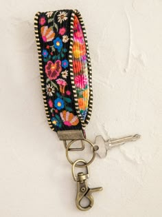 a keychain with flowers on it hanging from a hook against a white wall