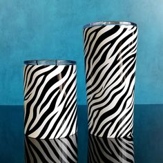 two black and white vases sitting next to each other on a blue tablecloth