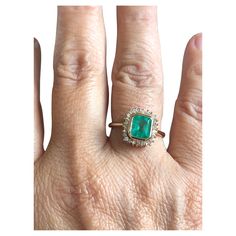 a woman's hand with an emerald and diamond ring