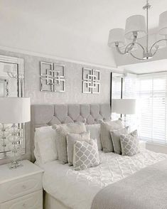 a bedroom with white bedding and silver accents