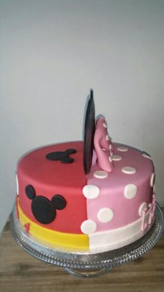 a cake with minnie mouse on it sitting on a wooden table next to a white wall