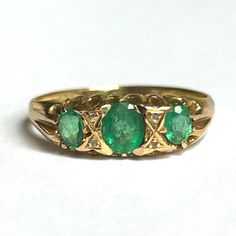 Victorian circa 1870s emerald and diamond trilogy ring in 18ct yellow gold The claw-set gemstones are earth-mined The three oval deep green emeralds (AA natural, not doublets) are well-cut and have good transparency, the central stone is 0.4 carat and the two sides stones are 0.2 carat each, total weight .80 ctw There are four rose-cut accent diamonds Stamped "W&FR" which stands for Walter & Frank Rabone, Birmingham-based gold- and silversmiths active from the early Victorian era The gold grade Antique Emerald Ring, Antique Rings Victorian, Diamond Trilogy Ring, Trilogy Ring, Victorian Rings, Multi Stone Ring, Multi Stone, Emerald Ring, 2 Carat