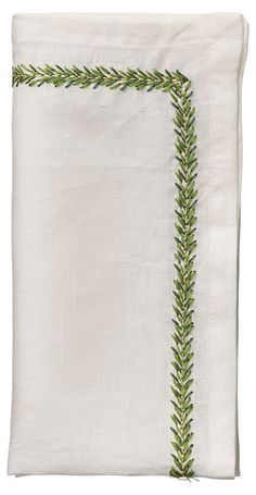 a white pillow with green trimmings on the edges and an embroidered border at the bottom