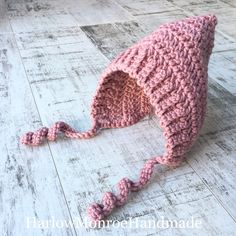 a pink crocheted hat on top of a wooden floor