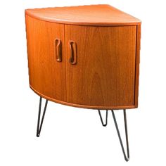 an orange cabinet with two doors and some hairpinks on the legs, against a white background