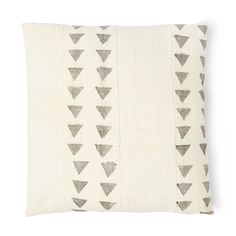 a white and grey pillow with black triangles on the front, sitting on a white surface