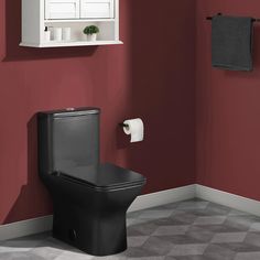 a black toilet in a bathroom next to a red wall with white towels on it