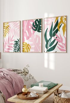 three paintings hang on the wall above a coffee table in a room with pink and green decor