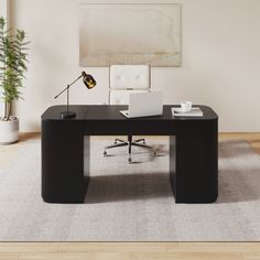 an office desk with a laptop on it in front of a large painting and potted plant