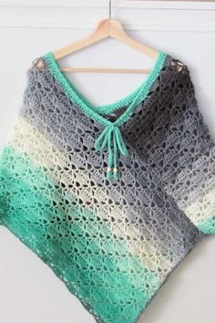 a crocheted sweater hanging on a hanger with a green and white top