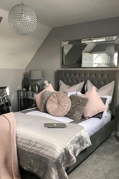 a bedroom with grey walls and white bedding, pink throw pillows and gray headboard