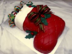 a red cake with white frosting and holly decorations on top, sitting on a bed