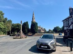 a silver car parked on the side of a road next to a tall building with a steeple in the background