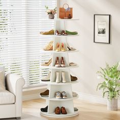 a room with a white couch and some shoes on a shelf in front of a window