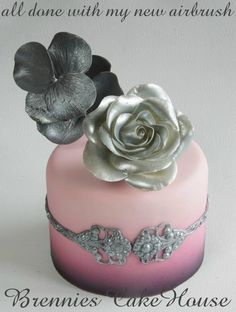 there is a pink cake with silver flowers on it and the words, all done with my new airbrush