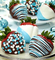 chocolate covered strawberries with blue and white decorations on them are sitting on a plate