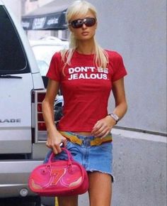 a blonde woman walking down the street carrying a pink purse