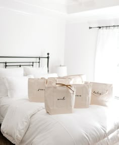 three bags sitting on top of a bed in a room with white sheets and pillows