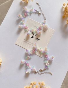 the necklace is decorated with pastel flowers and beads, along with a card that says you & me