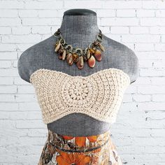 a mannequin with a crochet top and necklace on it's neck