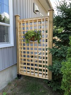 a wooden trellis with flowers in it on the side of a house next to some trees