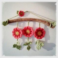 crocheted flowers hang from a branch