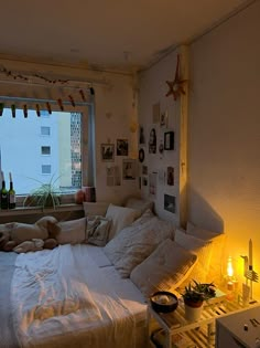 a room with a bed, window and pictures hanging on the wall next to it