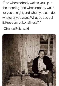 a man sitting on top of a wooden floor next to a wall with words above it