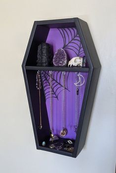 a black hexagonal shelf with jewelry hanging from it's sides on the wall