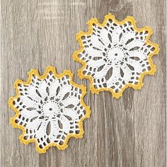 two yellow and white doily sitting on top of a wooden table