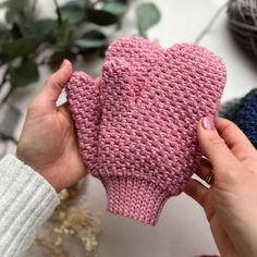 a person holding up a pink knitted mitt