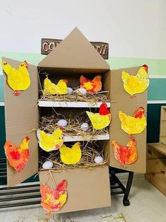 an open cardboard box with chickens and eggs in it