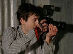 a man holding a camera up to his face with one hand and another in the other