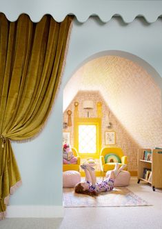 a person laying on the floor reading a book in a room with yellow drapes