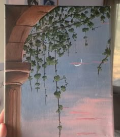 someone is holding up a painting that looks like vines and moon in the sky at sunset